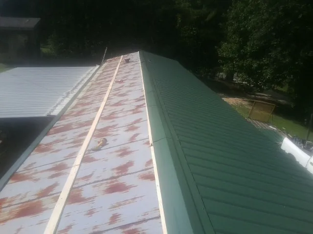 Old rusted panels beside newly installed green metal roofing — Wind Damage Roof Repair by Roofing Brothers in Galesburg